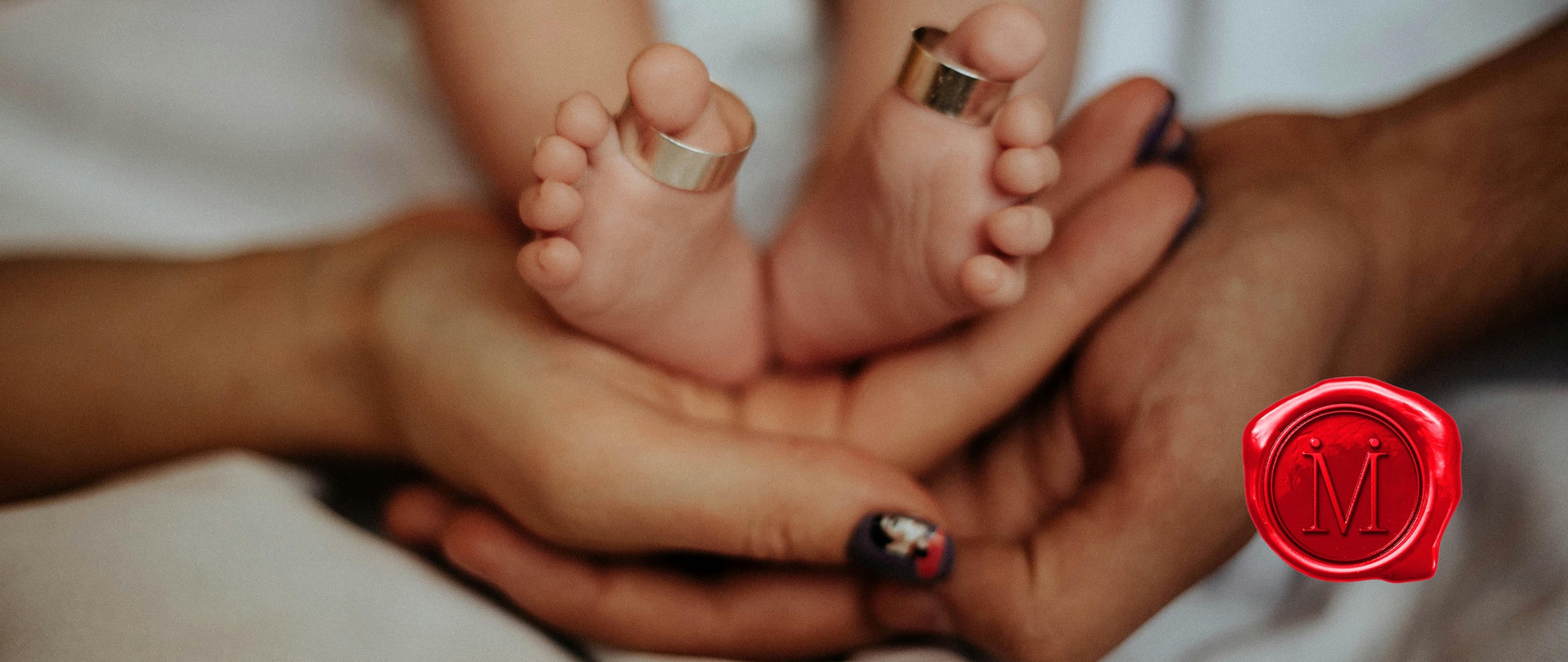 Two rings on baby's feet in mom's hands with ilMio icon in red wax