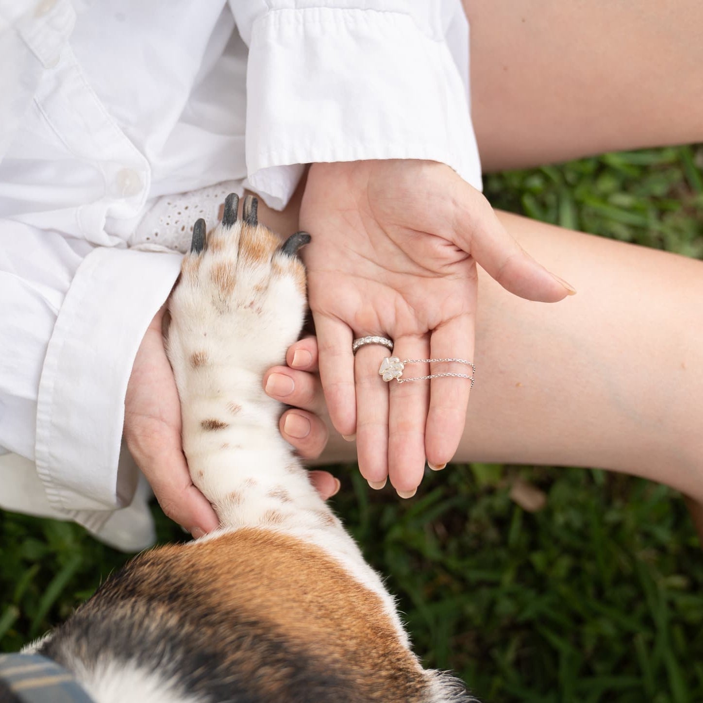 Woman holding ilMio Paw Necklace and holding dogs paw